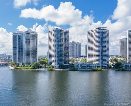 A picture of a town with high buildings with a lake from a drone